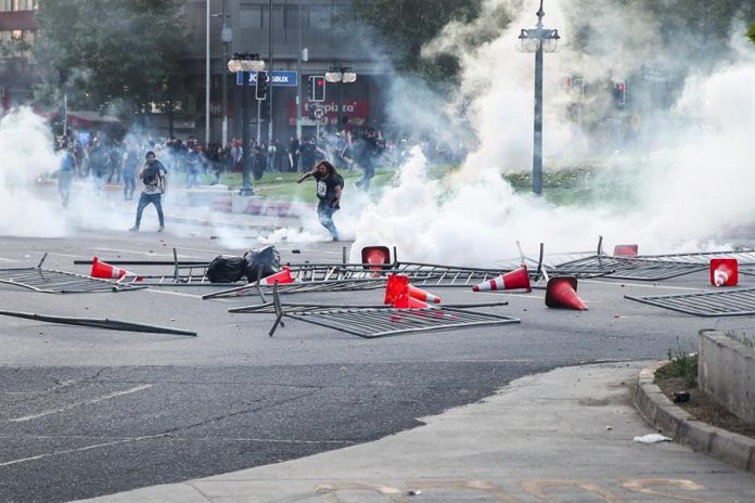 Manifestantes montan barricadas el viernes 18 de octubre en el centro de Santiago de Chile, en el contexto de las protestas contra el alza del boleto de Metro. | Foto: Efe/Alberto Peña