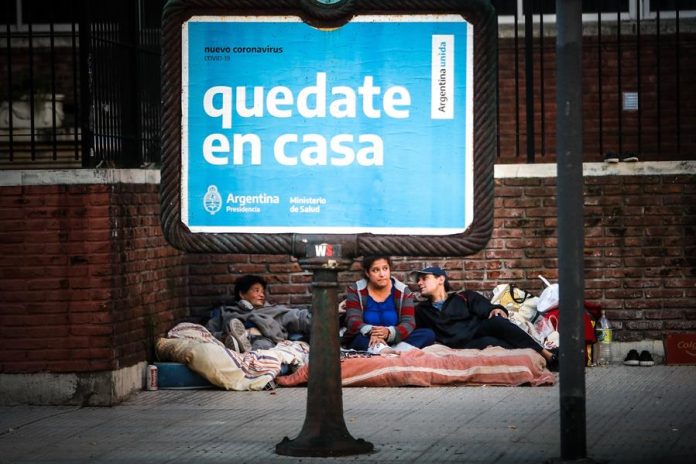 Una familia en condición de calle descansa tras una publicidad que invita a la ciudadanía a quedarse en casa este domingo, durante un nuevo día de cuarentena obligatoria por la pandemia de COVID-19, en Buenos Aires, el domingo 3 de mayo de 2020. Foto: Efe/Juan Ignacio Roncoroni.